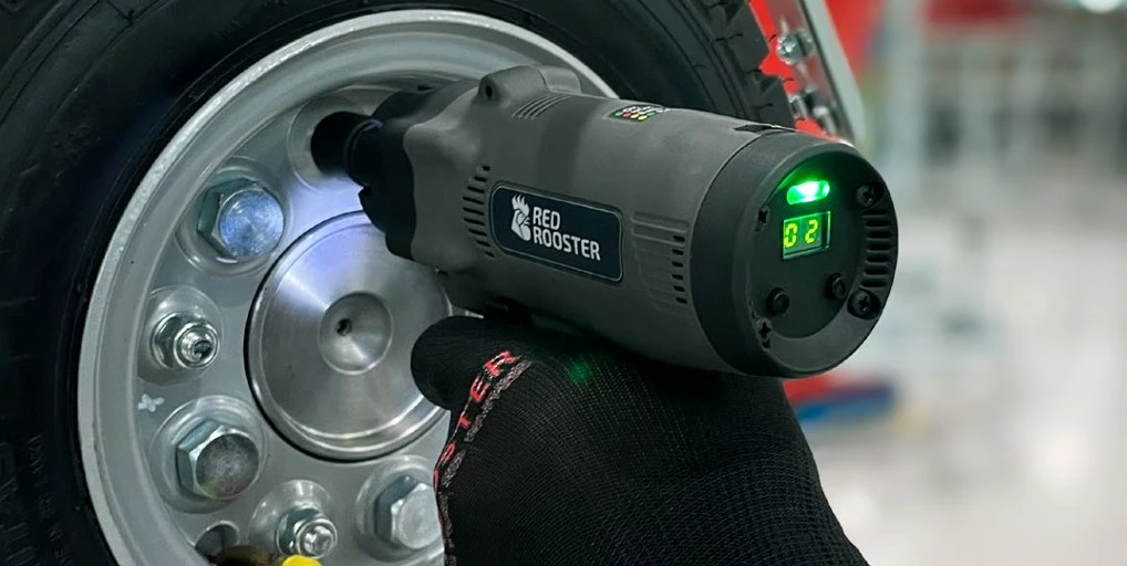 Llave de impulso neumática Red Rooster ajustando las tuercas de una rueda en un montaje industrial.